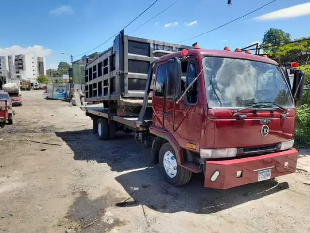Camión rojo de plataforma con carga estacionado en un patio
