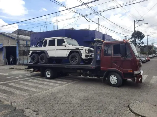Camión de plataforma transportando una camioneta todoterreno blanca